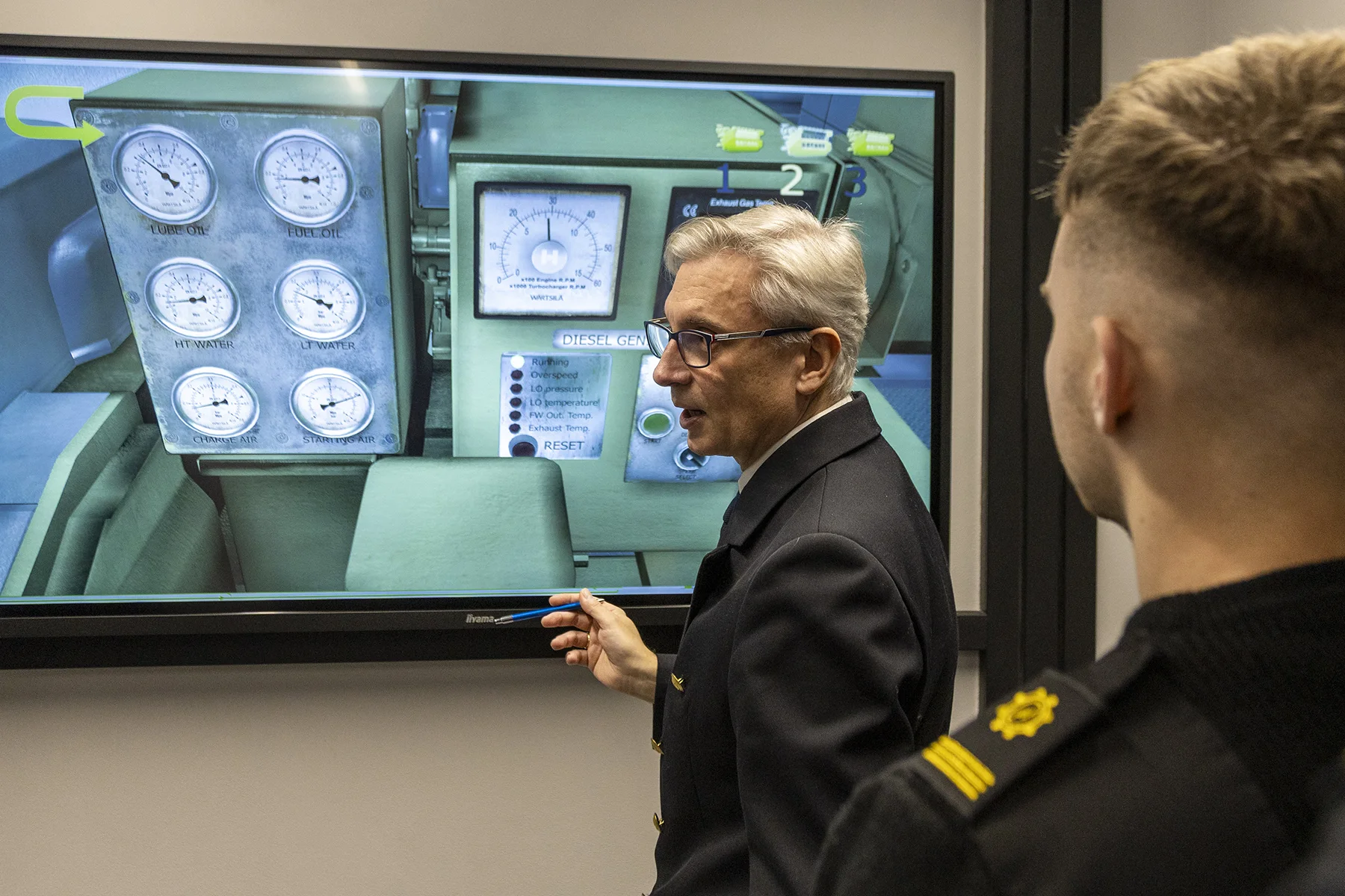 Wykładowca i student mechatroniki PM przed ekranem z widokiem interaktywnej siłowni okrętowej