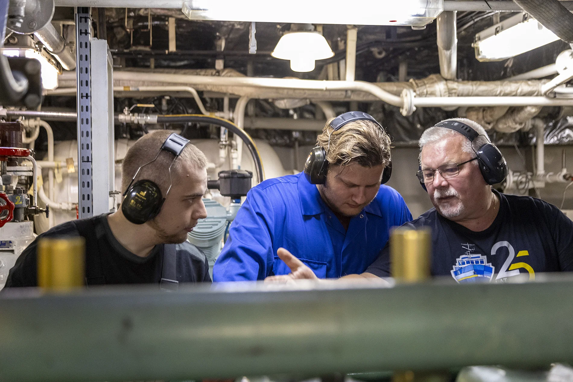 2 studentów i pokładowy elektryk podczas praktyk w siłowni okrętowej statku Nawigator XXI