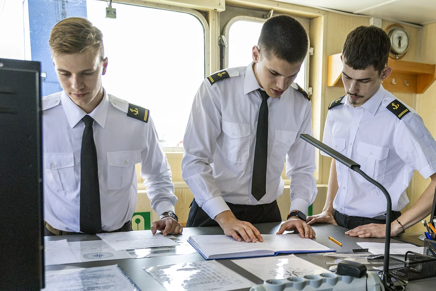 Troje studentów kierunku nawigacja na Politechnice Morskiej w Szczecinie podczas praktyk na mostku nawigacyjnym na statku Nawigator XXI