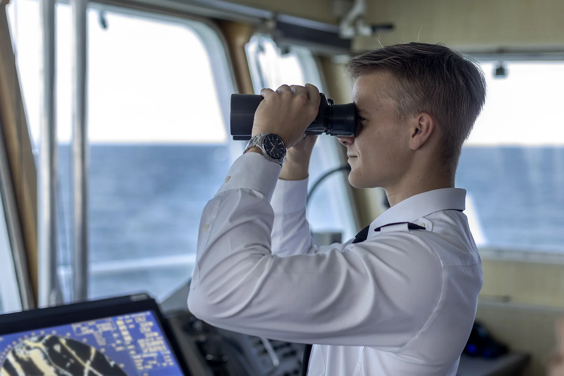 Student patrzy przez lornetkę z mostka nawigacyjnego