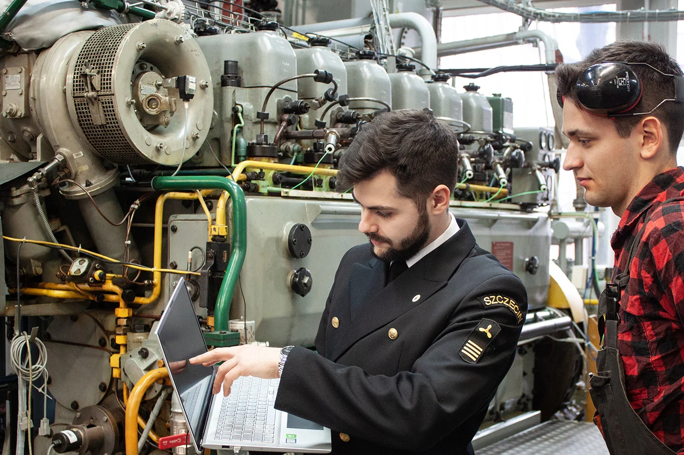 Dwoje studentów z laptopem przy silniku okrętowym