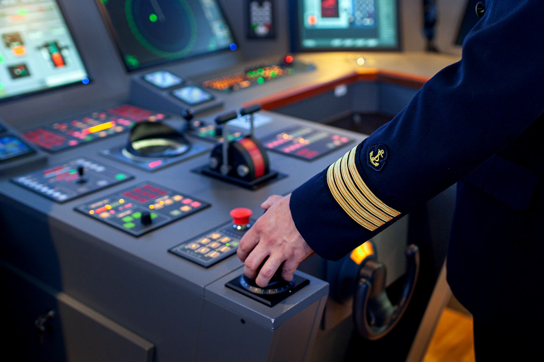 Hand in Master Mariner's uniform on ship's bridge simulator instruments