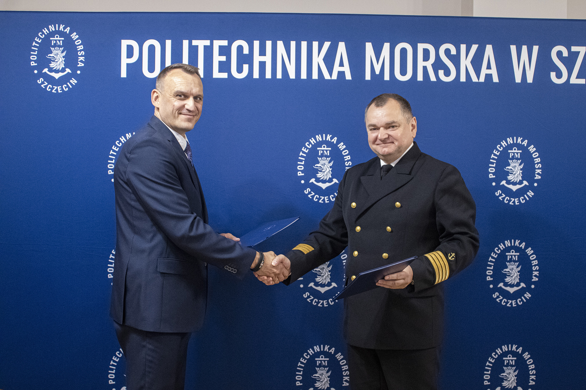 Dyrektor ZSBiKU Tomasz Wójcik i Rektor PM Wojciech Ślączka po podpisaniu listu na tle ścianki PM