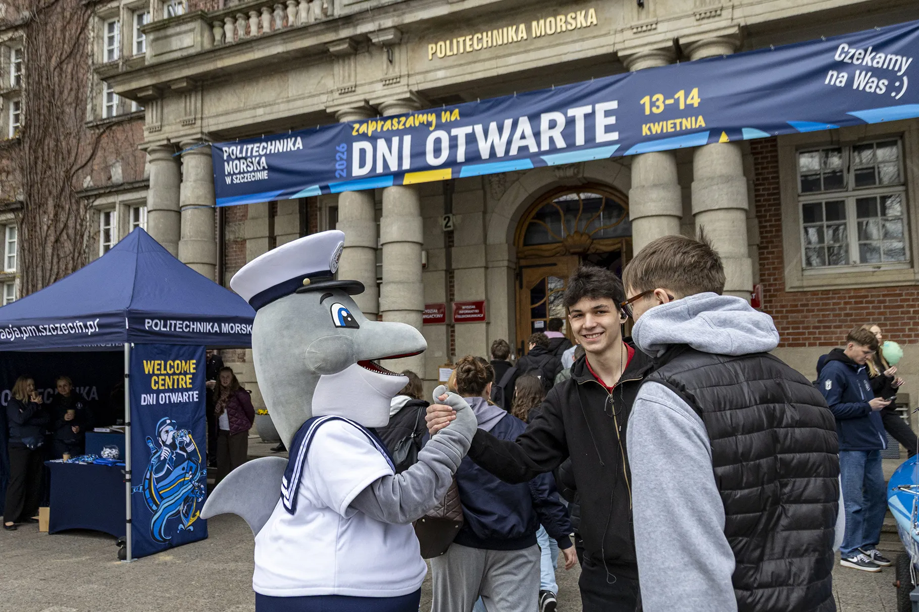 Maskotka PM Michu z kandydatami przed budynkiem uczelni podczas dni otwartych