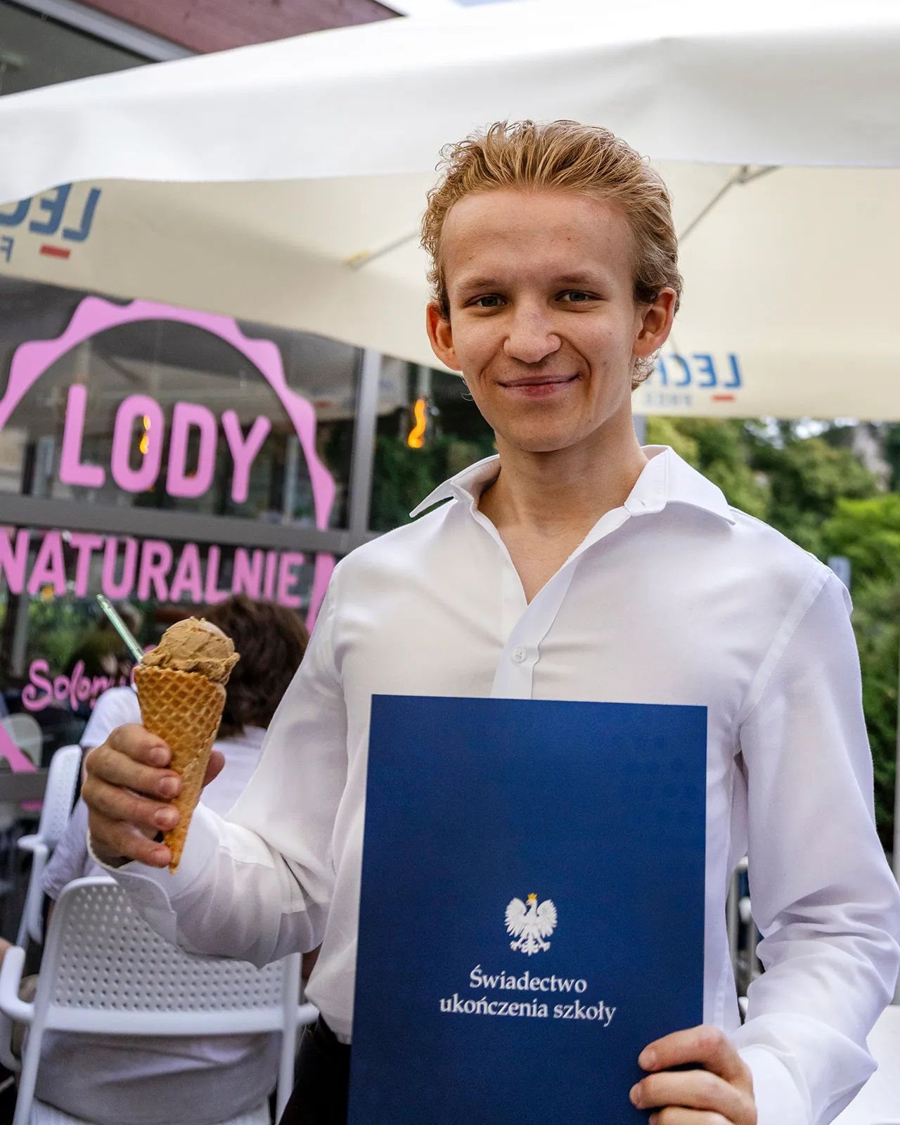 Maturzysta z teczką Świadectwo ukończenia szkoły z lodem w lodziarni Solony Karmel
